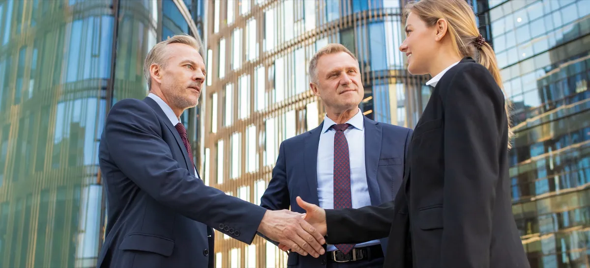 Three colleagues meeting outside a glass office building